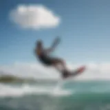 A kiteboarder gliding across the water under a clear blue sky