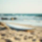 A sleek foil surfboard resting on a sandy beach under a clear sky