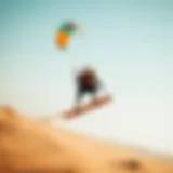 A dynamic shot of a kite landboarder soaring across a sandy landscape with a colorful kite above.